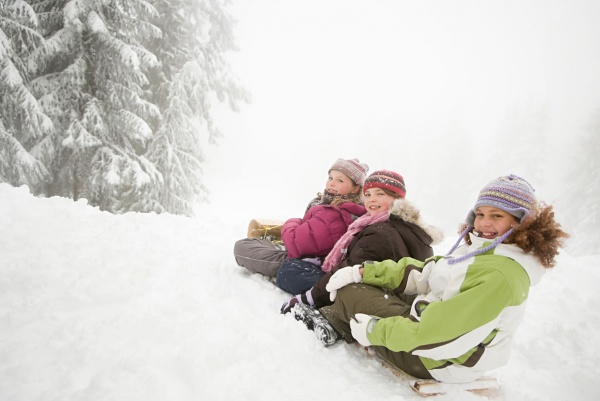 Eine Rodelpartie mit der Familie durch den tief verschneiten Wald